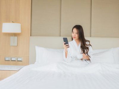 Portrait beautiful young asian woman with smart mobile phone in bedroom interior